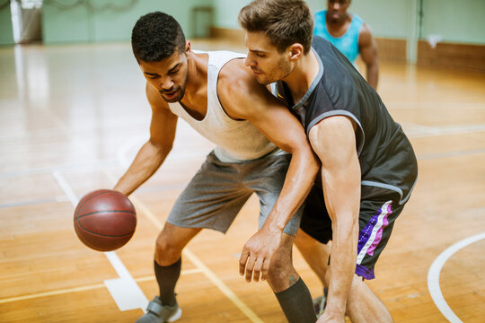 Young people playing basketball in an indoor basketball gym