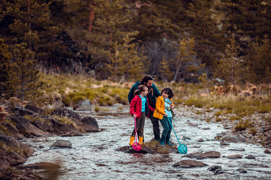 Single father net fishing with his daughter and son at a small river or creek