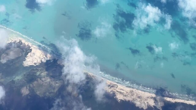 VARADERO, CUBA - DECEMBER 20, 2023: View from the porthole on the Atlantic coast of Cuba. View of the turquoise ocean water and islands with snow-white sand from the plane. White clouds over the water