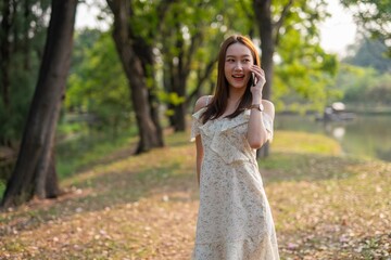 Beautiful woman using phone in a greenery park during sunset