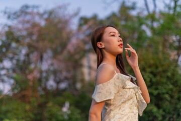 Beautiful young asian woman enjoying nature and sunset breeze at a park