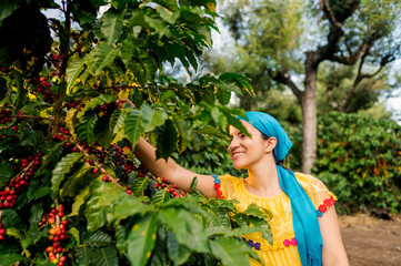 A happy female farmer collects coffee beans.