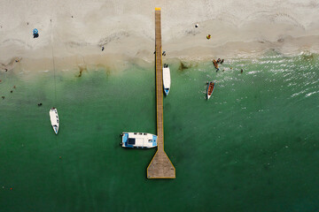 Botes y embarcaciones en el muelle a la orilla de la playa - obrazy, fototapety, plakaty