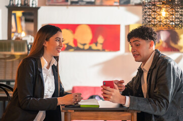 Friends talk and share good times. They show each other photos on their smartphone and they both look at them.