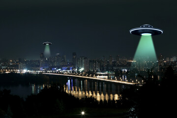 UFO. Alien spaceships emitting light beams over night city