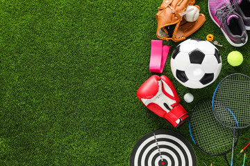 Different sport equipment on green grass, flat lay. Space for text