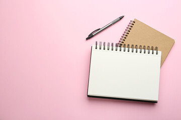Notebooks and pen on pink background, top view. Space for text