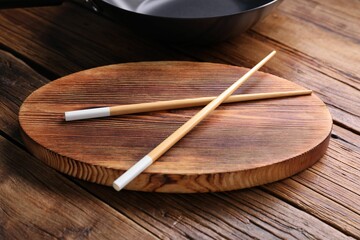 Serving board with chopsticks on wooden table, closeup