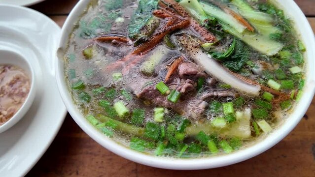 Traditional Vietnamese pho soup with beef slices, noodles, and fresh herbs in a bowl, Vietnamese cuisine concept