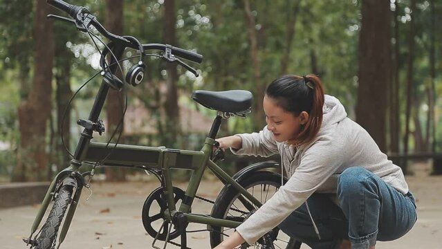 Chilling and relaxed young Asian woman in casual comfy clothes riding a bicycle on the bike lane in the park. hobby and exercise concept