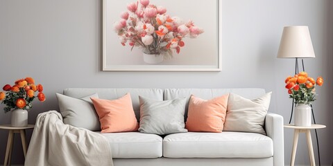 Flowers near grey settee with pillows in apartment with poster and lamps. Real photograph.