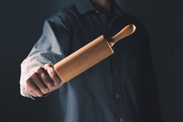 Man in work clothes also holds a rolling pin in his hand.