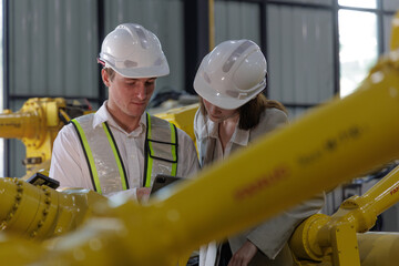 Fototapeta premium Engineers Collaborating on Factory Floor Amidst Robotics Equipment