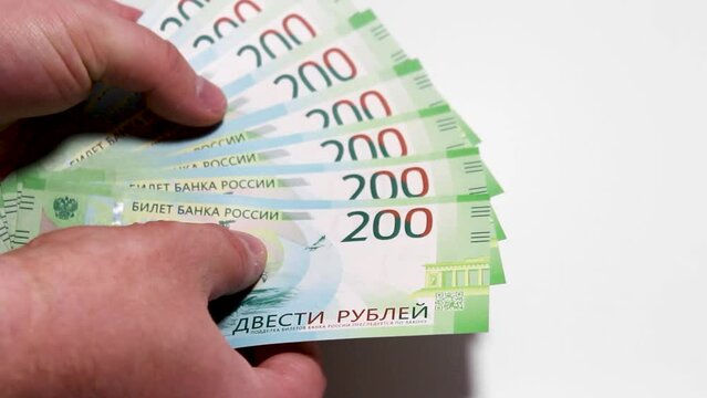 Closeup 4K video. Male hands count paper Russian green banknotes of 200 rubles. Russian cash money. Two hundred rubles of Russia. Concept for accounting, immigration, receiving payment, travel, tax