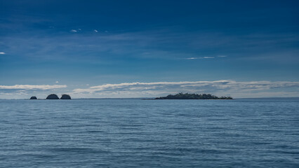 Endless blue ocean and azure sky with light clouds. Tropical islands are visible on the horizon. Ripples on the water. Madagascar