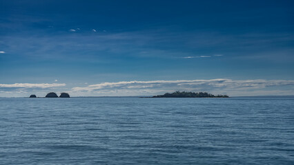 Endless blue ocean and azure sky with light clouds. Tropical islands are visible on the horizon....