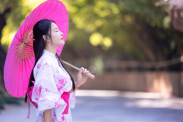 Asian woman wearing japanese traditional kimono. Beautiful Woman smiling, holding a umbrella...