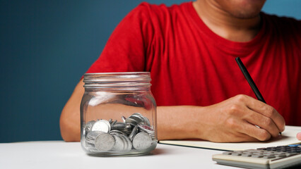 man with coins in a clear transparent glass jar. saving money concept