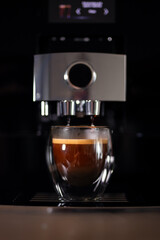Coffee machine making espresso in a glass on a black background