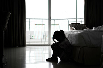 In the dark, a sad little girl sat on the floor in the bedroom. family violence family problems...