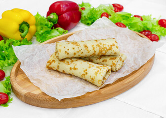 Homemade pancakes with filling on a wooden board