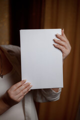 Creative start: a blank piece of paper waiting for inspiration. White sheet of paper in female hands. Place for an inscription on a psychological theme. White sheet of paper in female hands.
