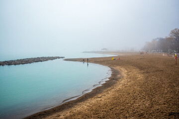 dog walkers on a foggy beach in winter shot kew beach toronto room for text	
