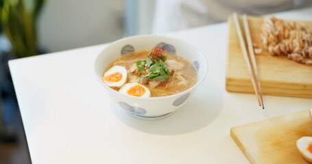 Ramen noodles, eggs and chopsticks on table in restaurant for lunch, meal or diet in plate. Bowl, food and nutrition with soup in cafeteria with catering service for dinner, snack or health in Tokyo