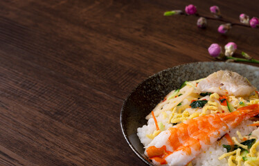Chirashi sushi and peach blossoms on the table. テーブルの上のちらし寿司と桃の花