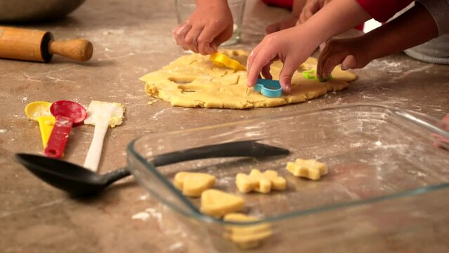 manos de ni&ntilde;os latinos amasando pasta de harina para preparar hornear galletas y cortando figuras para hornearlas