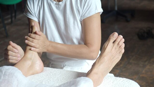 masseuse female therapist perform foot relaxing massage to senior 60s 70s caucasian short haired woman in spa setting