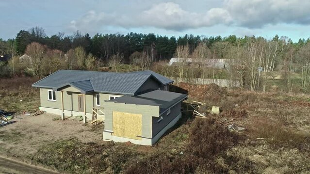 Aerial drone rotating shot over newly-built wooden houses surrounded by very few houses on a sunny morning.