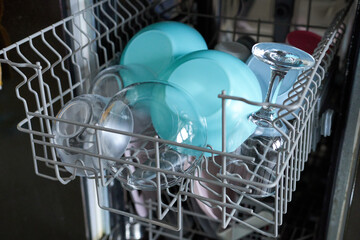 Open dishwasher with clean utensils in it, closeup