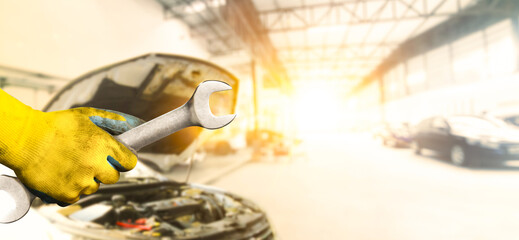 Mechanic hand holding a wrench in the auto repair center with sunlight and copy space , Car...