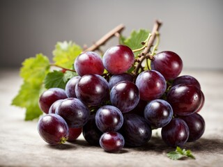Fototapeta premium Bunch of red grapes with green leaves on a wooden table