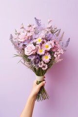 A bouquet of purple and pink flowers held in a person's hand