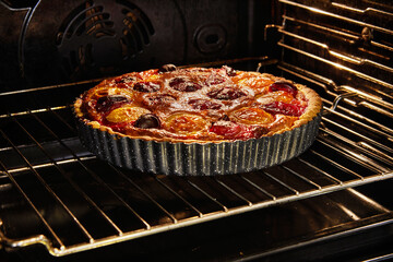 Mouth-watering image of a homemade plum pie being baked in an electric oven. The pie is filled with freshly made plum jam and exudes a delicious aroma