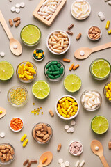 Big amount of colored capsules of vitamins, minerals and dietary supplements, lime as a source of natural vitamins from above on a light grey background. Happy and healthy lifestyle.