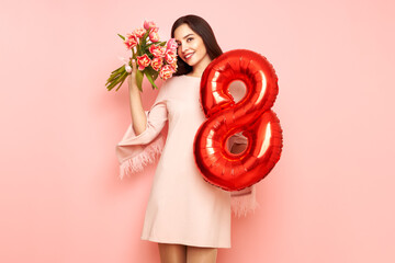 Beautiful young woman hold bouquet of tulips flowers and balloon number 8, rejoices spring holiday....