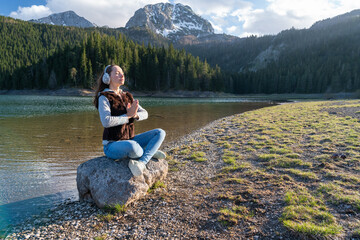 woman is practicing yoga in lotus pose at mountain lake