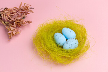 Nest with colored Easter eggs on the pink background.
