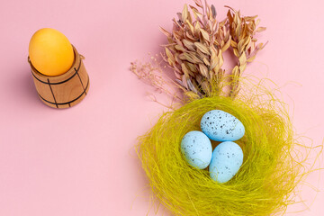 Nest with colored Easter eggs on the pink background.