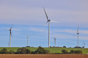 Wind turbines with landscape of agricultural fields under blue sky. Green energy concept.