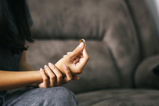 Woman holding wedding ring. Divorce concept.