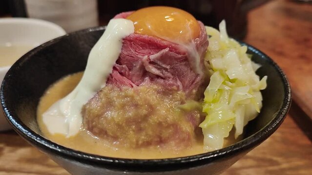 Closeup footage of roast kobe wagyu beef with raw egg with garlic sauce in a bowl