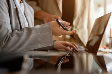 A businesswoman working on her laptop computer and discussing work with her colleague in the office.