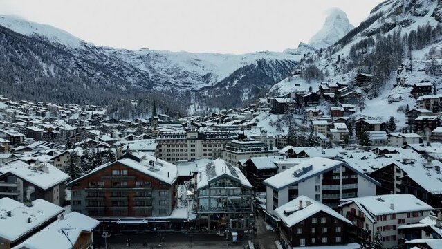 Slow drone rising up over the town of Zermatt, Switzerland on a winter day. Matterhorn and Ski resort in the background.