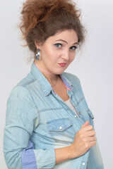 Portrait of a beautiful young woman in a denim shirt with a sly look.