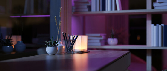 A hardwood desk in a modern, dimly lit room at night with a table lamp on the table.