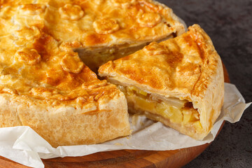 Layered Swiss pie with apple, potato, pear, onion and cheese close-up on a wooden board on the...